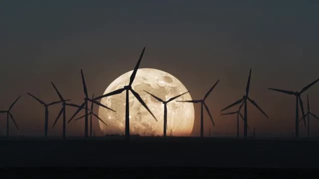 Wind Turbine Silhouettes Against Massive Full Moon at Night