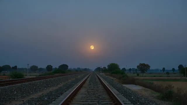 Scenic Railway Tracks Converging Toward Bright Full Moon at Twilight