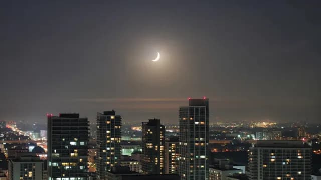 Night Cityscape with Crescent Moon Above Illuminated Skyscrapers