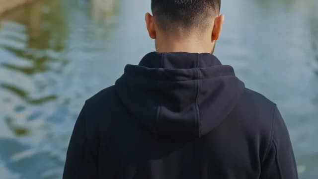 Back View of Man in Black Hoodie Near Water