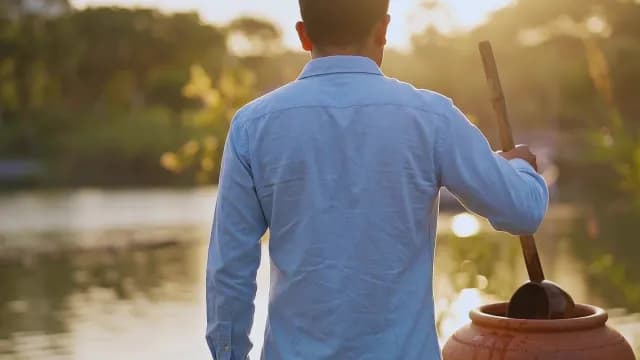 Man Using Traditional Water Dipper by Lake at Golden Hour