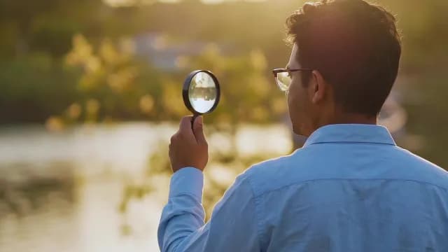 Man Examining Nature with Magnifying Glass at Sunset