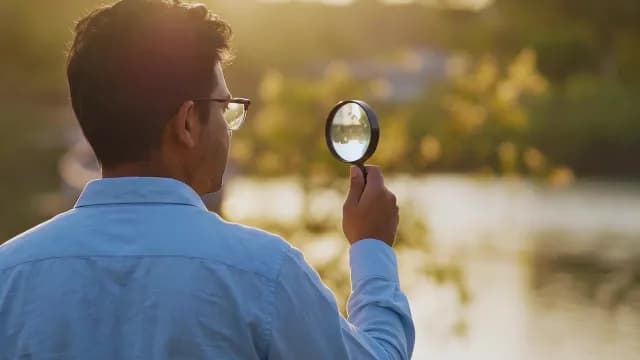 Man Investigating Nature with Magnifying Glass at Sunset