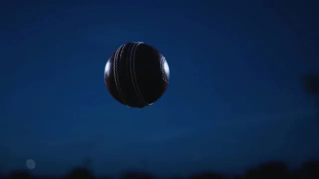 Red Leather Cricket Ball Flying Through Air Against Night Sky