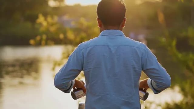 Man Pouring Traditional Drink at Sunset by the Lake