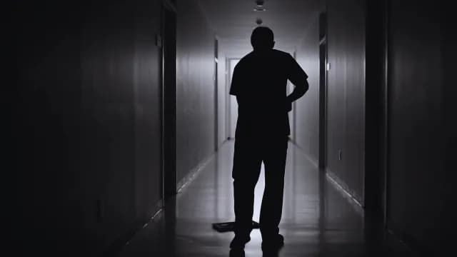 Silhouette of a Medical Professional in a Dimly Lit Hospital Corridor