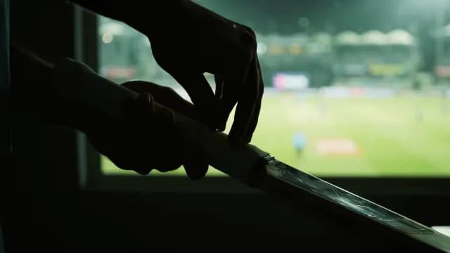 Cricket Player Silhouette Preparing Bat with Stadium Background at Night