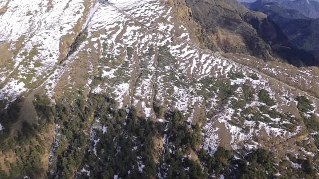 Aerial View of Snow-Capped Mountain Slopes and Winding Hiking Trail Chopta Uttarakhand