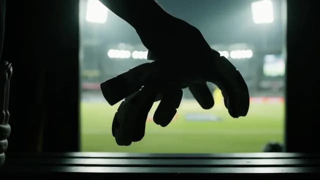Silhouette of Soccer Goalkeeper Holding Gloves Before Match at Night Stadium