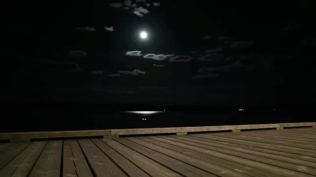 Full Moon Reflecting on Calm Water from a Wooden Pier at Night