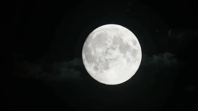 Bright Full Moon Glowing Against a Dark Night Sky with Clouds