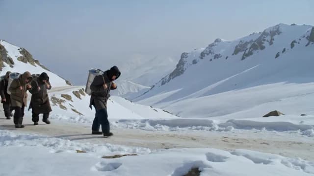 Men Carrying Heavy Milk Canisters Through Snowy Mountain Pass