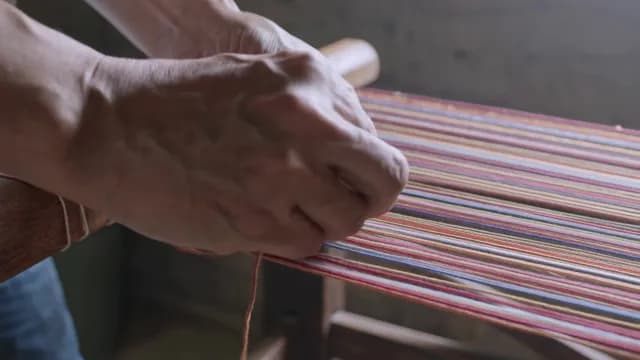 Close-Up of Artisan Hands Weaving Colorful Fabric on Traditional Wooden Loom