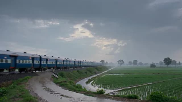 Indian Railway Train Passing Through Scenic Green Fields on a Cloudy Day