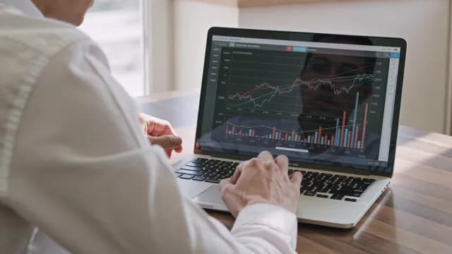 Professional Trader Monitoring Real-Time Stock Market Trends on Laptop