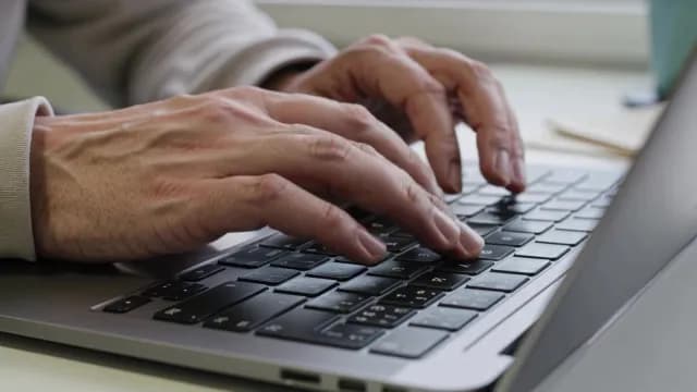 Close-Up of Hands Typing on Laptop Keyboard in Modern Workspace
