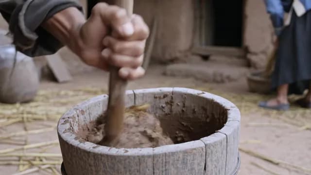 Close-up of Person Mixing Clay in Traditional Wooden Mortar