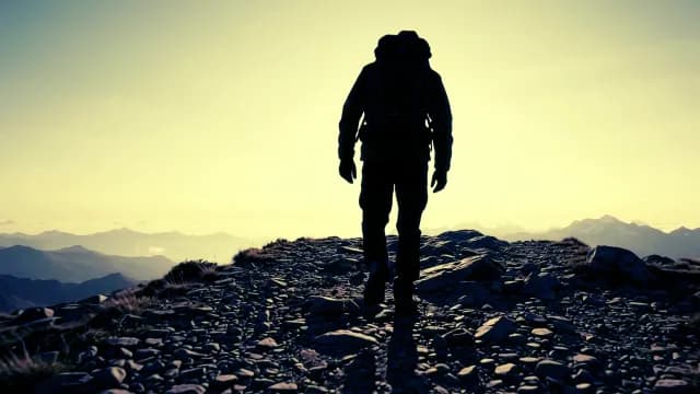 Silhouette of Hiker Walking on Mountain Ridge at Sunrise