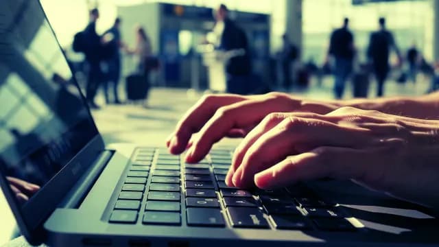 Digital Nomad Working on Laptop in Busy Airport Terminal