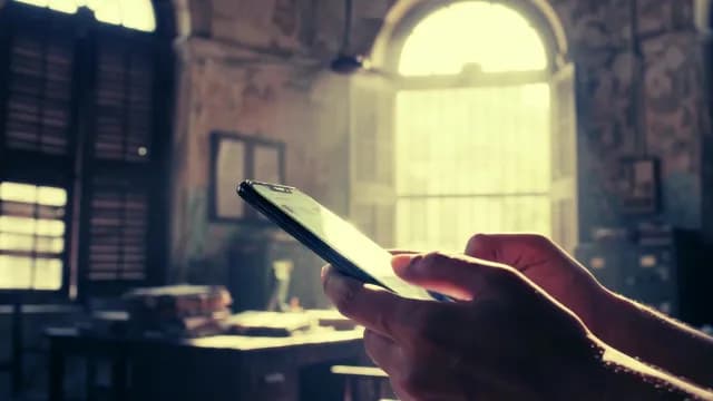 Person Using Smartphone in Vintage Office with Dramatic Sunlight