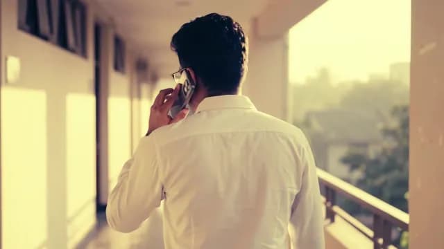 Professional man talking on smartphone while walking through a bright corridor