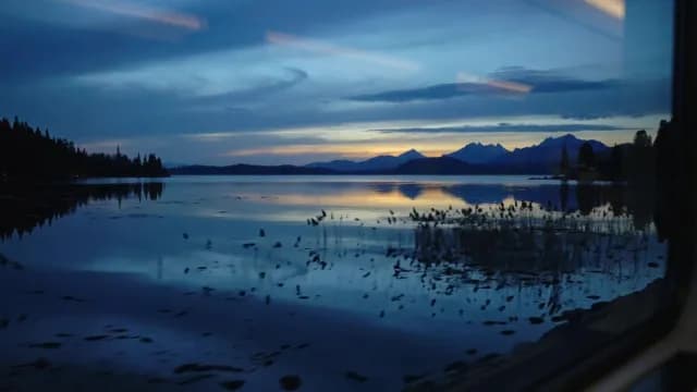 Scenic Mountain Lake View Through Train Window at Sunset